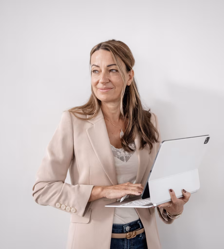 Jennifer Zanker mit Tablet, lächelnd an einer hellen Wand